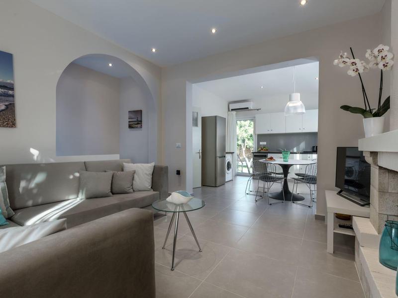 Spazio abitativo moderno con divano, tavolo da pranzo e cucina luminosa e aperta.