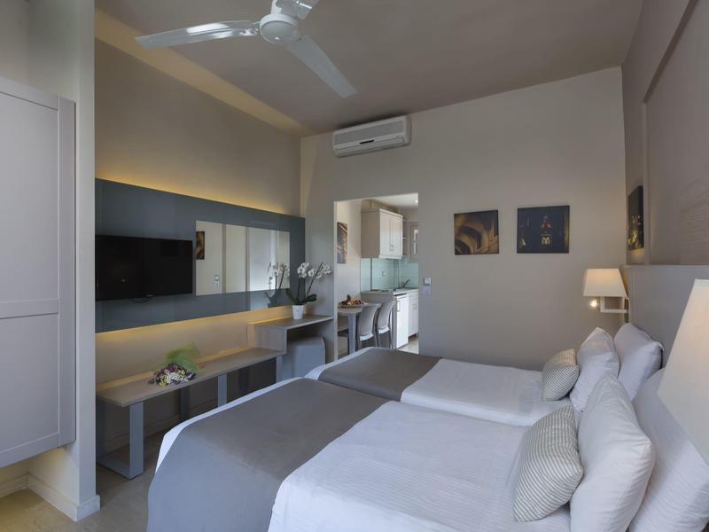 Camera d'hotel moderna con due letti singoli, scrivania e aria condizionata.