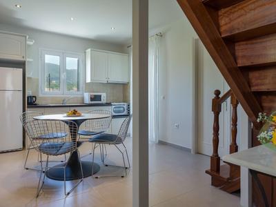 Helle Küche mit Essbereich, weißen Schränken, blauem runden Tisch und Treppe aus Holz.