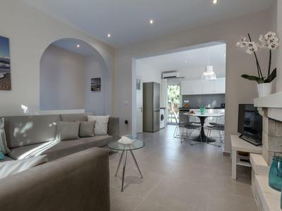 Helles Wohnzimmer mit grauer Sofa, kleinem Tisch und Blick in die offene Küche.