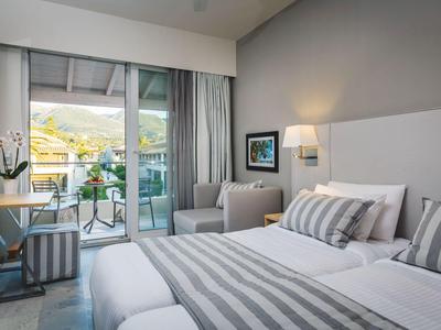 Modernes Hotelzimmer mit bequemen Betten, Sitzecke und Balkon mit Ausblick.