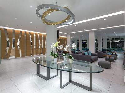 Moderne hotelhal met glazen tafels, bloemen, stijlvolle zitplaatsen en houten wanddecoratie