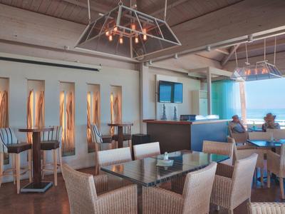 Helles Restaurant mit modernem Design, Glas- und Korbmöbeln, Blick auf das Meer.