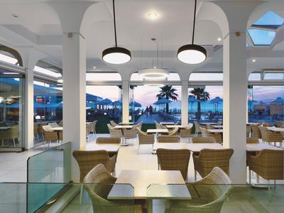 Modern hotelinterieur met uitzicht op palmbomen en zonsondergang.