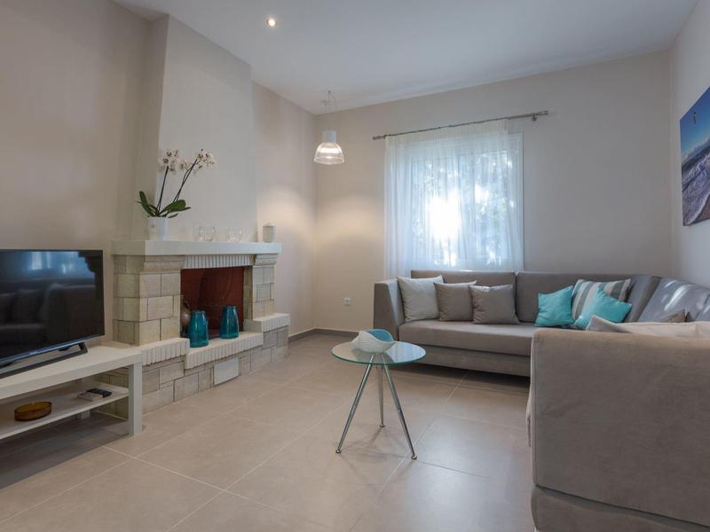 Modernes Wohnzimmer mit Kamin, TV, Sofas und dekorativen Kissen.