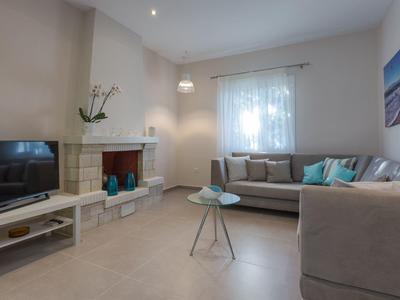 Modernes Wohnzimmer mit Kamin, TV, Sofas und dekorativen Kissen.