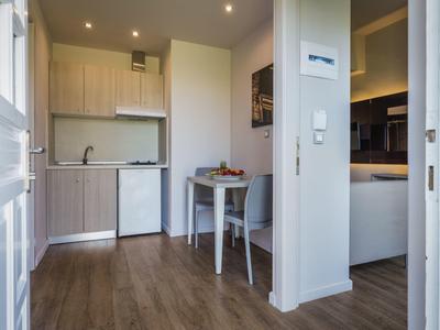 Kleine Küchenzeile mit Holzfront, Tisch und moderner Ausstattung in einem Hotelzimmer.