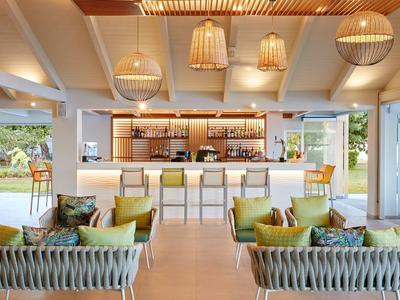 Modernes Hotelbar-Interieur mit hellen Möbeln, Körben und einer offenen Terrasse im Hintergrund