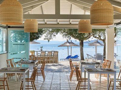 Open restaurant met houten meubels met uitzicht op strand en zee bij zonsondergang.