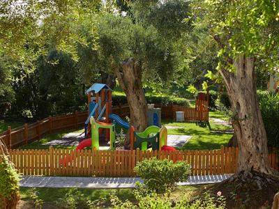 Bunter Kinderspielplatz mit Rutsche und Schaukel, umgeben von Bäumen und Holzzaun
