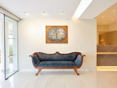 Elegantes Wartezimmer mit blauem Samtsofa, hellem Boden und modernen Beleuchtungselementen.