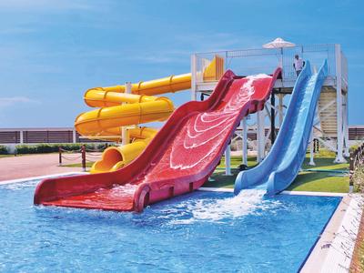 Colorful water slides lead into a swimming pool under a blue sky.