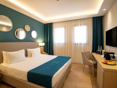 Modernes Schlafzimmer mit großem Doppelbett, runden Spiegeln an der Wand und Schreibtisch mit Fernseher.