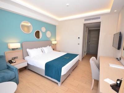 Schlafzimmer mit blau-weißer Wand, Doppelbett, Nachttischen, Sessel und Schreibtisch mit Stuhl.