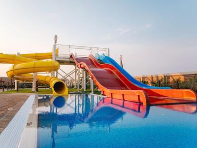 Mehrfarbige Wasserrutschen führen in einen klaren blauen Pool mit glattem Wasseroberfläche.