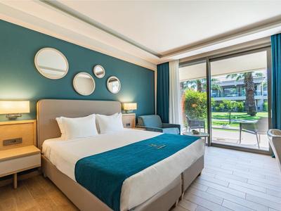 Helles Schlafzimmer mit großem Bett, blauer Wand, runden Spiegeln und Terrasse mit Gartenblick.