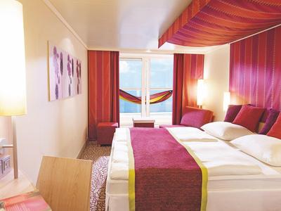 Modernes Hotelzimmer mit zwei Betten, roter Dekoration und Blick auf das Meer.