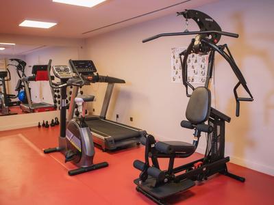 Piccola palestra con varie attrezzature per allenamento e uno specchio a parete.