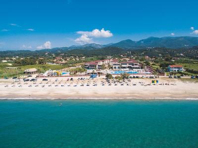 Strand mit Sand, Sonnenschirmen, Gebäuden im Hintergrund und bewölktem Himmel über Bergen.