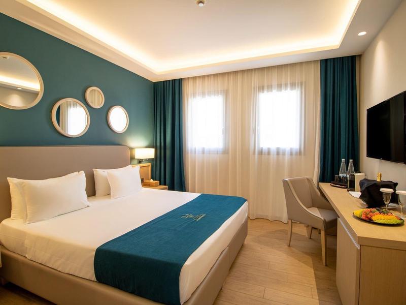 Modernes Schlafzimmer mit großem Doppelbett, runden Spiegeln an der Wand und Schreibtisch mit Fernseher.