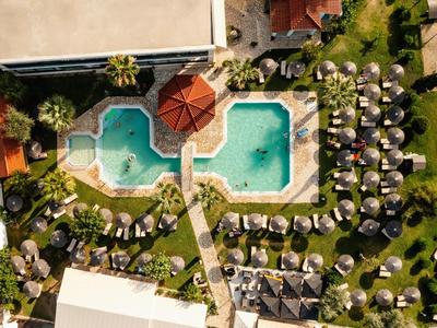 Luftaufnahme eines Pools mit Liegestühlen und Sonnenschirmen in einem Hotelresort.
