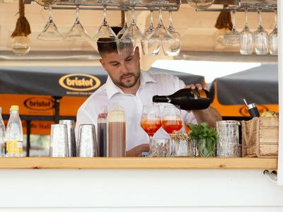 Barman schenkt drankjes in een bar met flessen en glazen op de achtergrond.