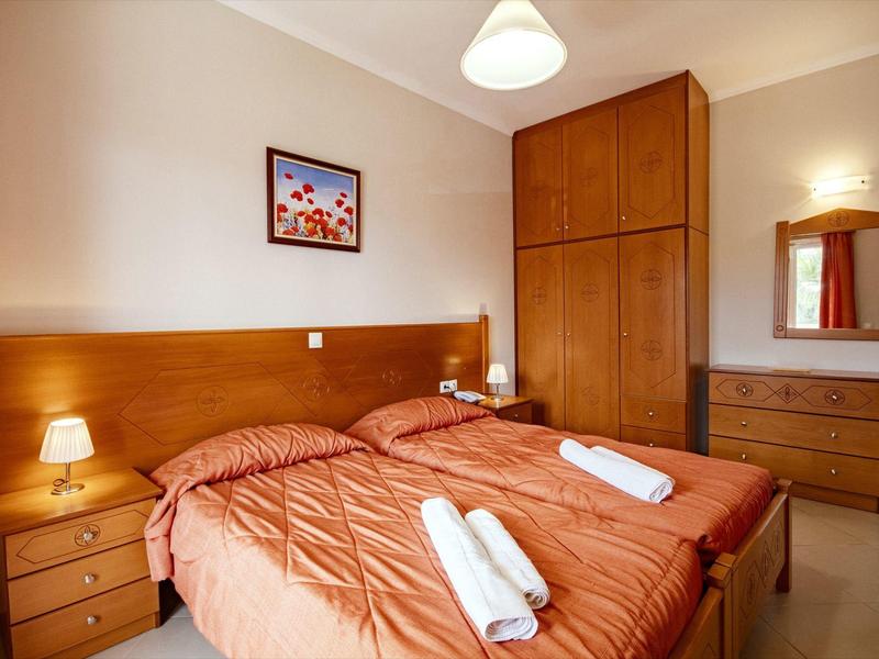 Hell eingerichtetes Schlafzimmer mit Doppelbett, Holzmöbeln und warmem Licht.