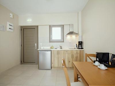 Kleine Küchenzeile mit Holzschränken, Mini-Kühlschrank, Kaffeemaschine und Esstisch mit zwei Stühlen.