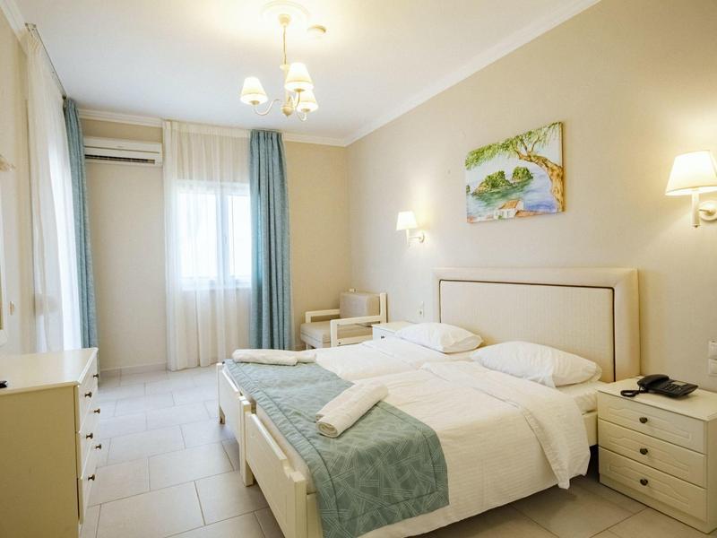 Helles Schlafzimmer mit Doppelbett, zwei Nachttischen, Schreibtisch, Gardinen und Wandbild.