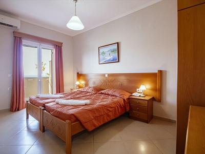 Schlichtes Schlafzimmer mit Doppelbett, roten Decken, Nachttischlampen und großem Fenster mit Vorhängen.