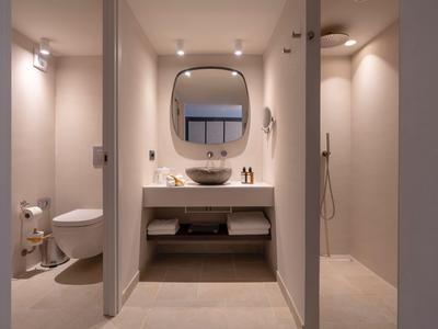 Bagno moderno con lavabo, WC e doccia aperta in tonalità neutre