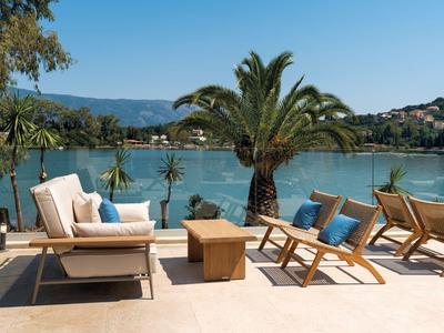 Terrazza con comode sedie e un tavolo con vista su palme e acqua.