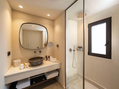 Bagno moderno dell'hotel con lavabo, specchio, doccia e finestra.