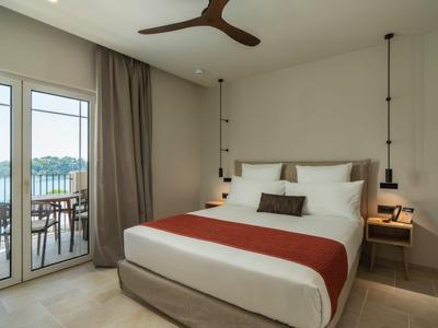 Modernes Schlafzimmer mit Doppelbett, Balkon und Blick auf das Wasser.