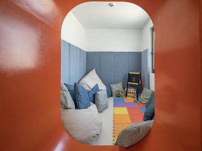 Blick durch einen roten Bogen auf einen gemütlichen Spielbereich mit bunten Matten und Kissen.