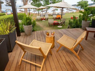 Two wooden chairs and a small table on a terrace overlooking lounge chairs and umbrellas in the garden.