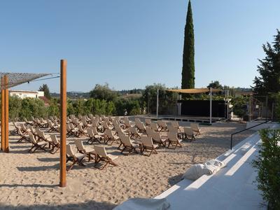 Sandy area with lounge chairs and trees in the background under clear sky