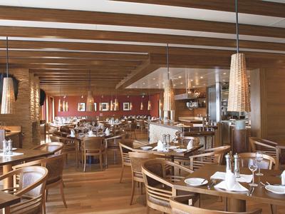 Großes, helles Restaurant mit Holzdecken, Holzmöbeln und gedeckten Tischen in warmen Farbtönen.