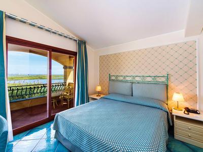 Modern hotel room with double bed and balcony overlooking the sea.