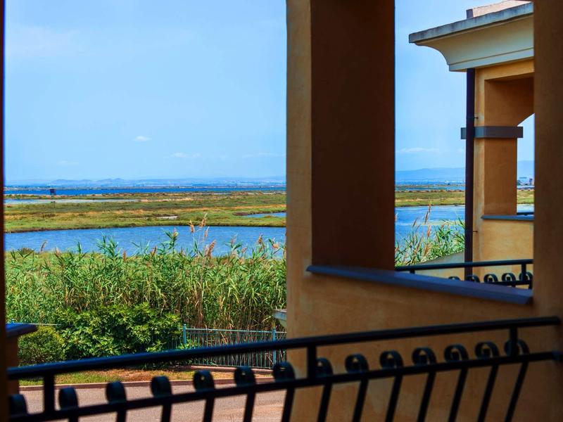 View from a balcony overlooking water, greenery, and a clear sky.