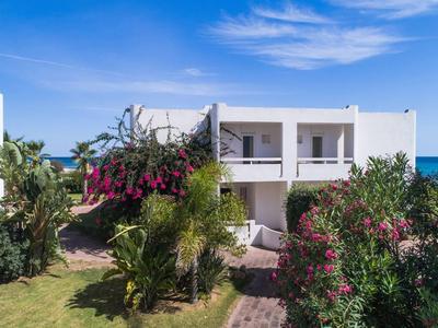 Zwei-Stockwerke-Strandhaus mit Garten und blühenden Blumen unter blauem Himmel