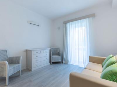 Helles Hotelzimmer mit weißen Möbeln, Vorhängen und grauem Bodenbelag