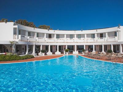 Hotel mit großem, klarem Pool und weißer Fassade unter blauem Himmel.
