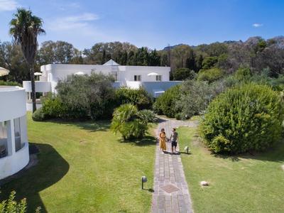 Blick auf einen Garten mit Wegen und weißen Gebäuden unter blauem Himmel.