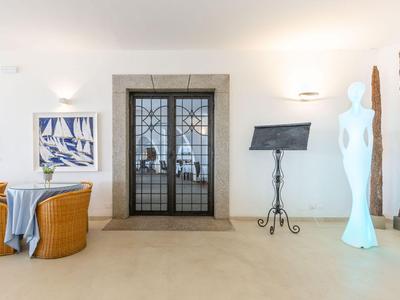 Moderner Hotel-Flur mit orangefarbenen Sitzgelegenheiten, Skulptur und Blick durch eine Glastür.