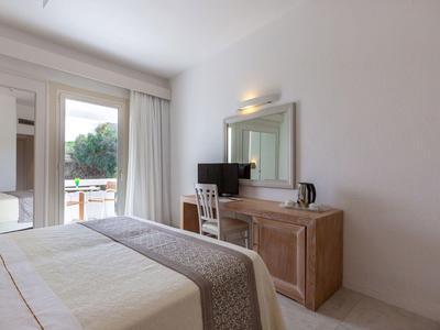 Helles Hotelzimmer mit Doppelbett, Holzmöbeln und Balkon mit Blick ins Grüne.