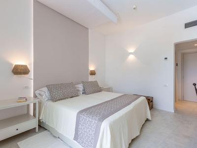 Helles Hotelzimmer mit Doppelbett, Nachttischen und moderner Beleuchtung.