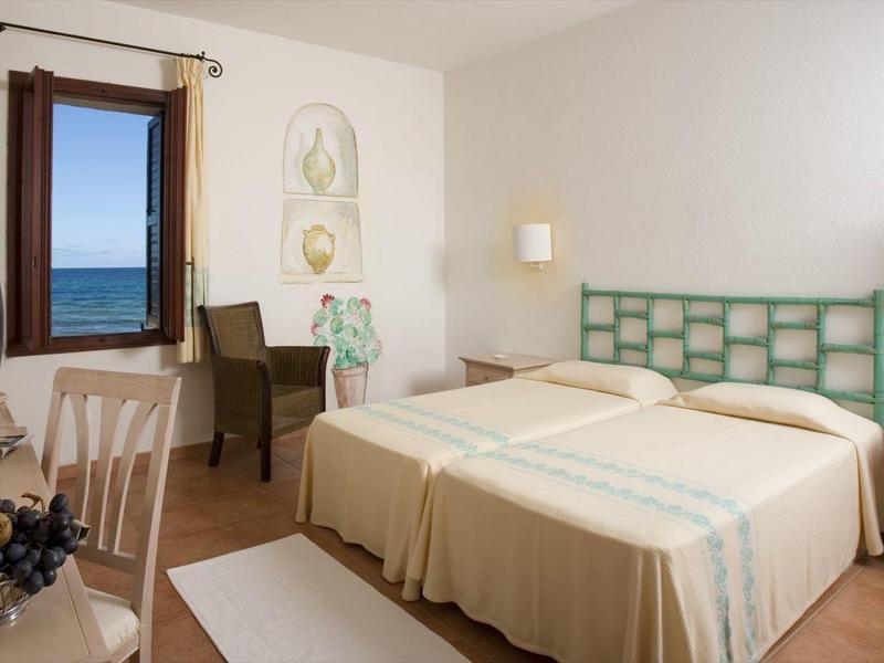 Helles Hotelzimmer mit zwei Einzelbetten, einem Schreibtisch, Fenster mit Meerblick und Fernseher.