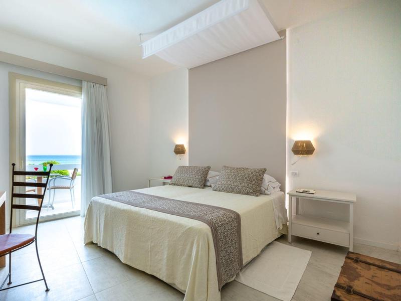 Helles Hotelzimmer mit Doppelbett, Balkon und Blick auf das Meer.