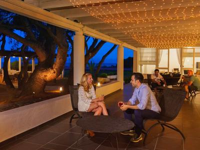 Abendliche Lounge mit beleuchteten Deckenlichtern und Gästen, die entspannt sitzen.